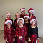 Lorilee with seven children in red Santa hats and plaid pajamas